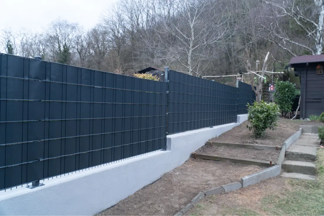 Doppelstabmattenzaun mit Sichtschutz auf einem Betonsockel mit stufen